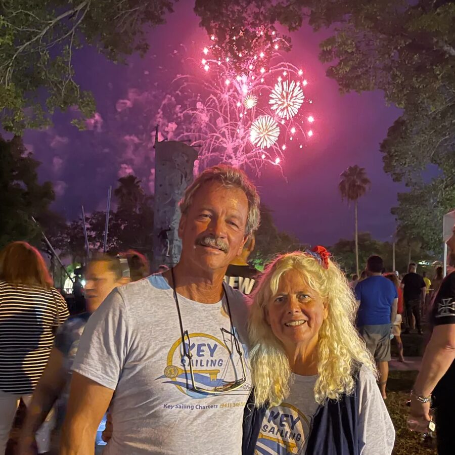 Captain Tim and Jan in Key Sailing shirts under fireworks in Sarasota