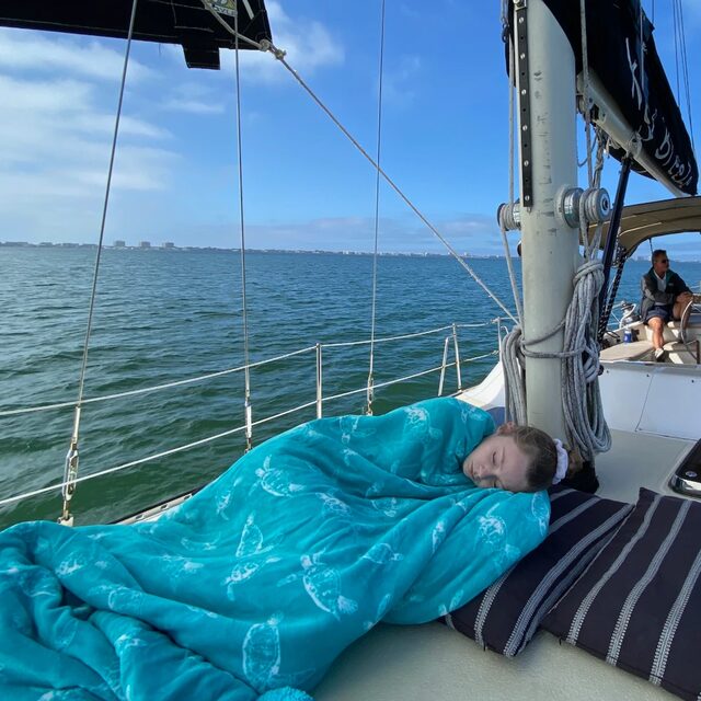Una joven huésped dormida en la cubierta bajo una manta turquesa