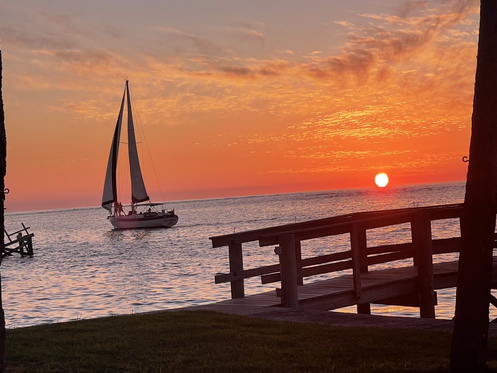 The Key Breeze sailing past a dock at sunset