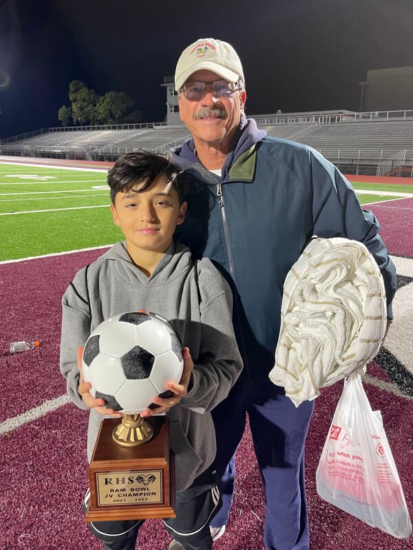 Captain Tim with his grandson and a soccer championship trophy