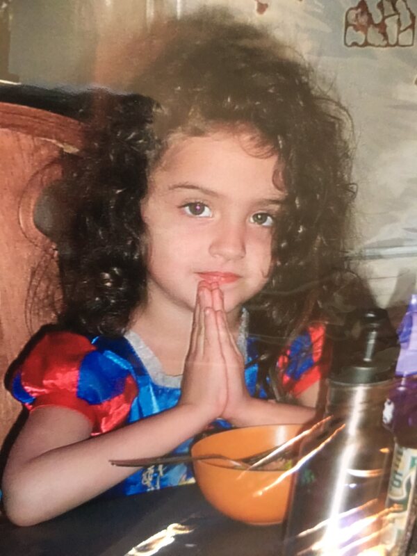 A young granddaughter folding her hands to say grace
